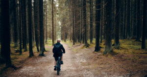 Man cycling in the woods. Embracing The Wild: How A Forest Escape Can Reset Your Mind