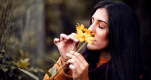 Woman smelling a flower. Embracing The Wild: How A Forest Escape Can Reset Your Mind