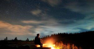 Man stargazing in front of the fire. Embracing The Wild: How A Forest Escape Can Reset Your Mind