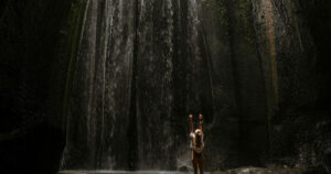 Woman admiring the forest waterfall. Embracing The Wild: How A Forest Escape Can Reset Your Mind